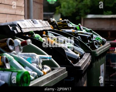 De nombreuses bouteilles en verre vides de différentes couleurs sont mises au rebut dans des récipients énormes. Beaucoup de déchets pour le recyclage dans l'arrière-cour d'un restaurant ou d'un bar. Banque D'Images