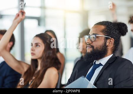 Toutes les questions sont les bienvenues. Un beau jeune homme d'affaires assiste à un séminaire avec ses collègues. Banque D'Images