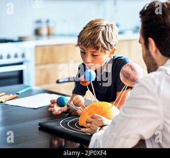 Encouragez les jeunes esprits à rester curieux. Un père aidant son petit fils avec un projet d'école à la maison. Banque D'Images