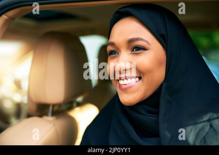 Elle a une bonne journée devant elle. Une jeune femme d'affaires gaie qui sort d'une voiture pour se rendre au travail pendant la journée. Banque D'Images