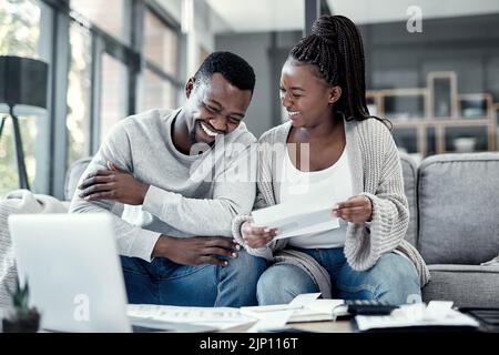 Bon couple noir payant des factures sur un ordinateur portable à la maison, en vérifiant leur budget et les économies. Un mari et une femme afro-américains souriants qui apprécient l'avenir Banque D'Images