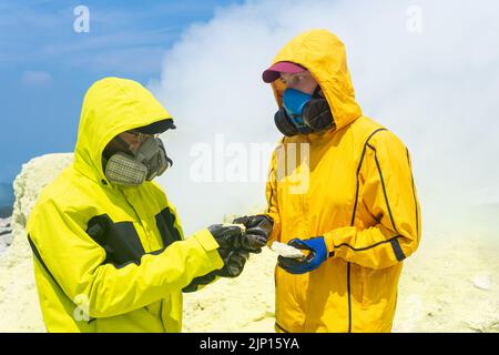 les volcans en pente du volcan examinent des échantillons de minéraux sur fond de fumaroles de soufre fumarales Banque D'Images