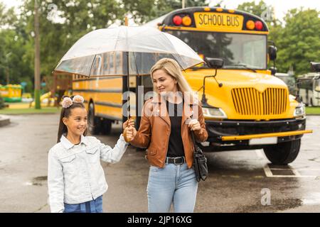 Éducation: Petite fille et mère près de l'autobus scolaire Banque D'Images