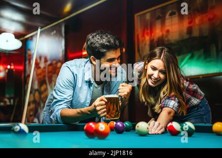 Un jeune couple heureux s'amuser en jouant au billard au bar. Concept de divertissement pour les personnes Banque D'Images