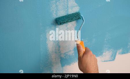 Décorateur peinture à la main des murs de couleur bleue avec rouleau Banque D'Images