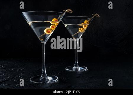 Martini, deux verres aux olives épicées, sur fond noir. Boissons froides Banque D'Images