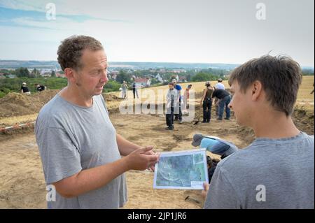 Helfta, Allemagne. 15th août 2022. Le directeur de l'excavation Felix Biermann (l.) et l'étudiant David Herz discutent de la suite de l'excavation. De vastes fouilles archéologiques se poursuivent sur une superficie de 1500 mètres carrés. Sur le site de l'ancien palais royal près de Helfta, des bâtiments majestueux seront découverts cette année. Credit: Heiko Rebsch/dpa/Alay Live News Banque D'Images