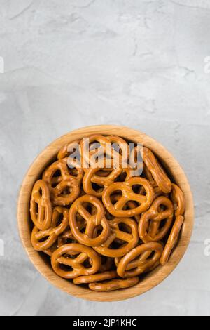 Mini-bretzels salés bavarois dans un bol en bois sur fond gris. En-cas traditionnel de bière en Allemagne. Vue de dessus, espace de copie Banque D'Images