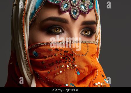 Studio photo d'une femme qui porte le hijab coloré décoré de sequins et de bijoux. Style arabe. Banque D'Images