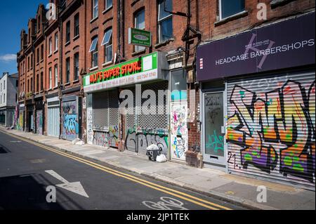 Grafitti sur un mur et des volets de magasin dans le quartier de Brick Lane à Londres Banque D'Images