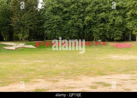 Muenster, Allemagne, 9 juillet 2022 la paix écrit en allemand avec des fleurs rouges dans un parc idyllique le matin dans le centre-ville Banque D'Images