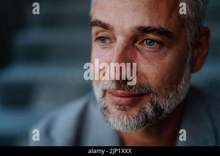 Portrait en gros plan d'un homme d'affaires charmant assis, regardant l'appareil photo. Banque D'Images