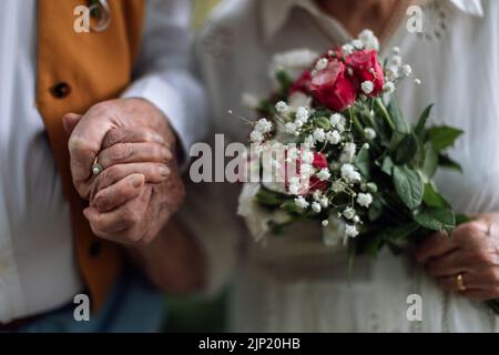 Gros plan des mains des aînés avec des anneaux de mariage pendant leur mariage. Banque D'Images