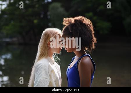 Les jeunes femmes passent du temps ensemble dans la nature, près du lac, concept d'amitié forte et durable. Banque D'Images