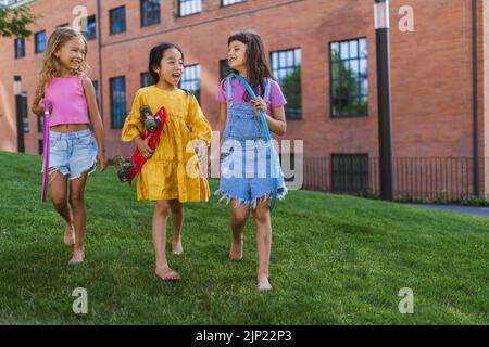 Des enfants heureux jouant et parlant ensemble dans le parc de la ville, pendant la journée d'été. Banque D'Images