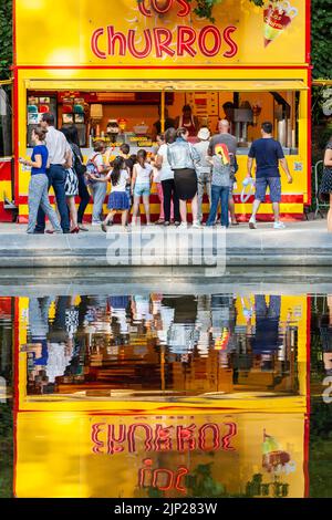 Les clients se sont regroupés devant un camion alimentaire offrant des churros et se sont réfléchis sur un morceau d'eau. Banque D'Images