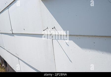 Un vieux mur blanc rustique en béton avec des clous dessus Banque D'Images