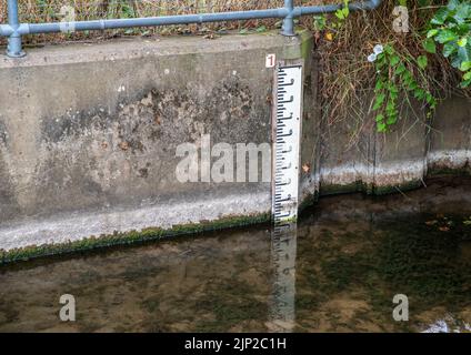 Indicateur de niveau d'eau de rivière à lignes noires et blanches, avec faible niveau d'eau. Banque D'Images