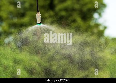 Arroseur agricole pulvérisant de l'eau à l'extérieur dans le jardin Banque D'Images
