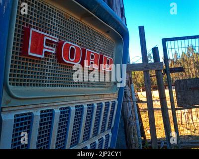 Un gros plan d'un logo rouge Ford sur un vieux tracteur de chantier à côté d'une clôture Banque D'Images