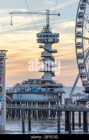 Un cliché vertical de la grande roue et du Piertoren sur la jetée de Scheveningse avec de beaux nuages de coucher de soleil en arrière-plan Banque D'Images