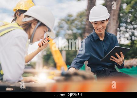 De jeunes architectes et ingénieurs asiatiques discutent de plans sur le chantier Banque D'Images