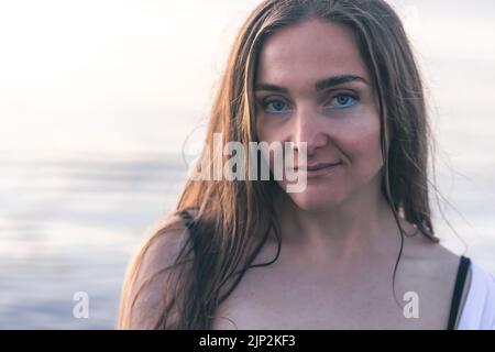 Portrait d'une jeune femme sur un fond flou de la mer. Banque D'Images