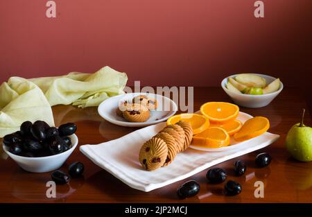 Plateau de fruits avec un mélange d'oranges fraîches, juteuses, sucrées, poires, jamun également appelé baies de prune Java et biscuits d'avoine placés sur une table en bois sombre comme b Banque D'Images
