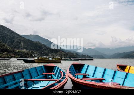 Les bateaux colorés amarrés contre les montagnes vertes et le ciel bleu. Pokhara, Népal. Banque D'Images