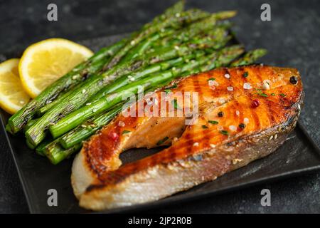 Steak de saumon grillé et asperges sur la poêle sur fond sombre. Gros plan Banque D'Images