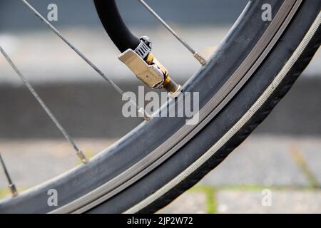 Un gros plan du gonflage d'un pneu à plat de vélo par tube avec valve de voiture à travers Banque D'Images