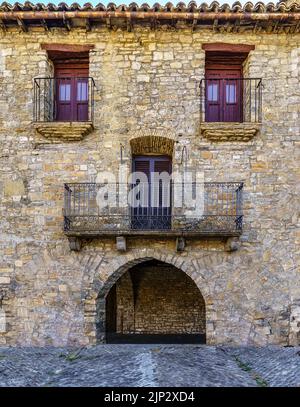 Ancienne façade de maison en pierre qui ressemble à un visage humain avec les yeux, le nez et la bouche. Ainsa, Espagne, Banque D'Images