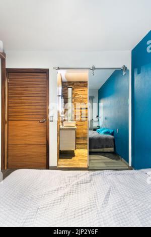 chambre, chambre, en arrière-plan vous pouvez voir une salle de bains, avec porte coulissante en miroir, porte en bois Banque D'Images