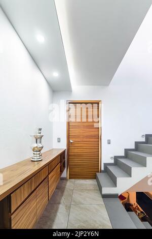 distributeur d'une maison moderne, avec escalier et lumière au pied, armoire de stockage en bois, porte en bois Banque D'Images