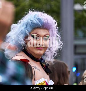 Braunschweig, Allemagne, 13 août 2022: Ancienne reine de drag avec une perruque de cheveux bleus et violets souriant au défilé de la CDD Banque D'Images