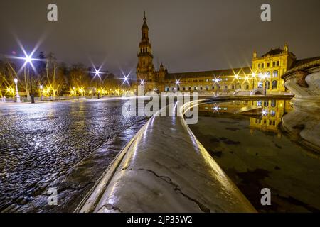 Plaza de España à Séville, scène nocturne après avoir plu avec une longue exposition photo et réflexions de lumières dans l'eau et rues pavées. Andalousie. Banque D'Images