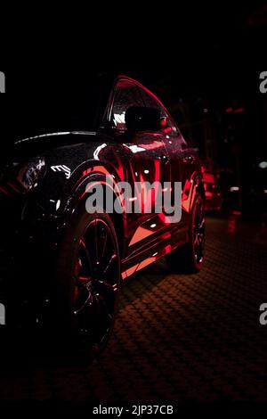 Lumière rouge reflétée dans le SUV Audi noir la nuit, Boch, Allemagne Banque D'Images