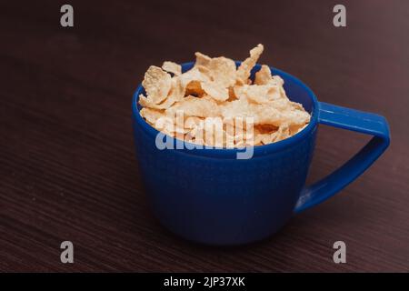 céréales de maïs servies dans une tasse, dans le cadre d'un petit déjeuner sain, en bois desaturated copie espace arrière-plan.vue rapprochée Banque D'Images
