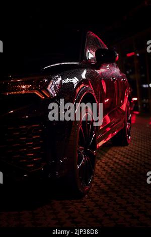 La lumière rouge se reflète dans le vus Audi noir la nuit Banque D'Images