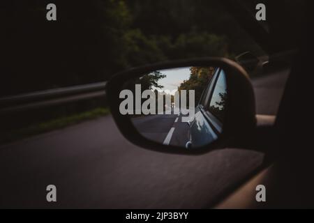 Un gros plan d'un rétroviseur d'aile reflétant l'arrière de la voiture pendant la conduite. Banque D'Images