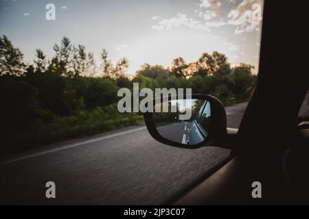 Un gros plan d'un rétroviseur d'aile reflétant l'arrière de la voiture pendant la conduite. Banque D'Images