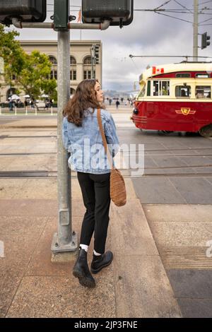 Portrait non posé d'une jeune femme qui attend de traverser une rue animée du centre-ville | Veste en Jean | San Francisco Wharf Banque D'Images