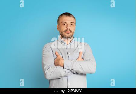 Prise de vue en studio d'un homme d'âge moyen sérieux sur fond bleu Banque D'Images