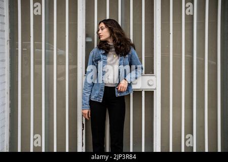 Portrait non posé de la jeune femme qui attend à la porte de sécurité d'Iron | porte | trottoir du centre-ville Banque D'Images