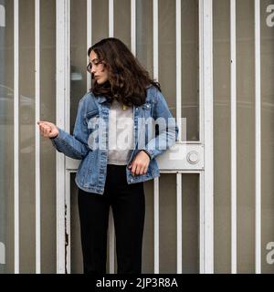 Portrait non posé de la jeune femme qui attend à la porte de sécurité d'Iron | porte | trottoir du centre-ville Banque D'Images