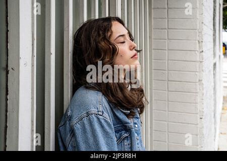 Portrait non posé de la jeune femme qui attend à la porte de sécurité d'Iron | porte | trottoir du centre-ville Banque D'Images