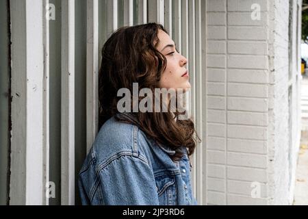 Portrait non posé de la jeune femme qui attend à la porte de sécurité d'Iron | porte | trottoir du centre-ville Banque D'Images