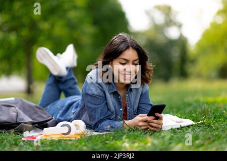 Portrait de la jeune femme arabe se détendant au parc avec un smartphone Banque D'Images
