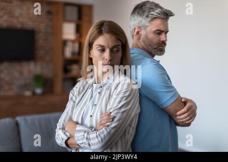 Contrarié offensé adulte mari européen ignore femme, homme et femme se tenir à l'arrière dans la chambre intérieure Banque D'Images
