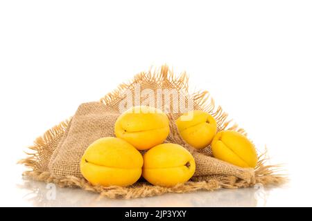 Plusieurs abricots jaune vif juteux d'ananas sur une serviette jute, macro isolée sur un fond blanc. Banque D'Images